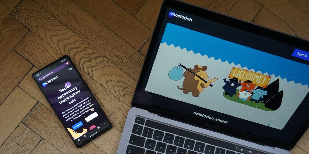 Un ordenador abierto mostrando el sitio web de Mastodon junto a un móvil